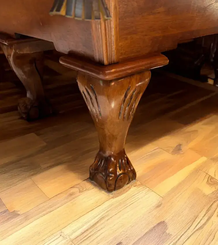 A carved clawfoot leg on a restored antique pool table