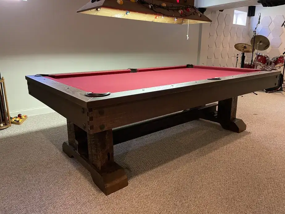 A red-cloth trestle pool table in a basement