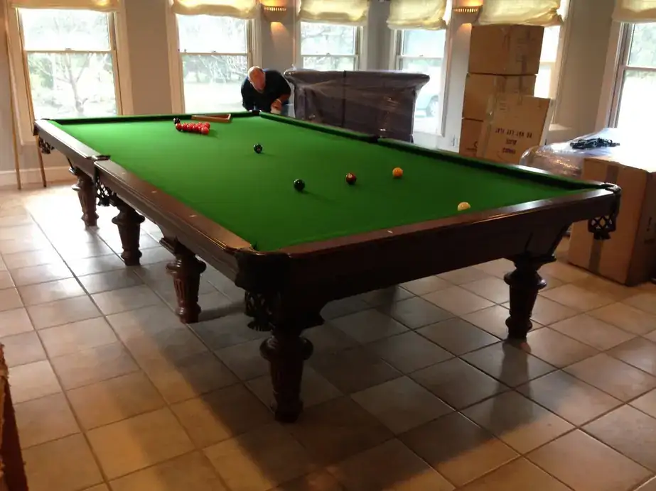 A 12-foot snooker table in green cloth on a tiled floor