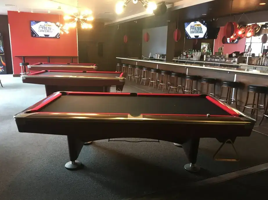 Two pool tables set up side by side in a bar room